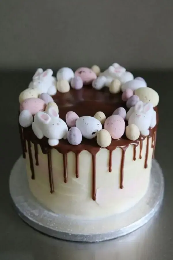 bolo de páscoa decorado com calda de chocolate e mini ovos coloridos Foto Deavita