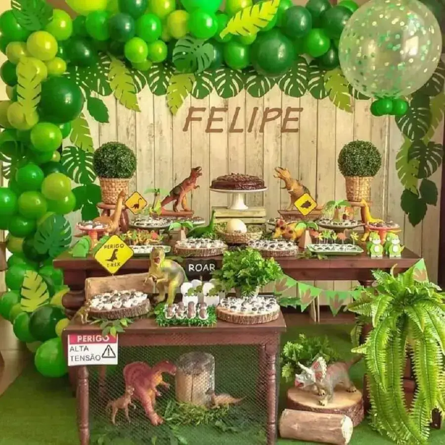 decoração festa dinossauro com painel de madeira decorado com folhagens e balões verdes Foto Andressa Oliveira