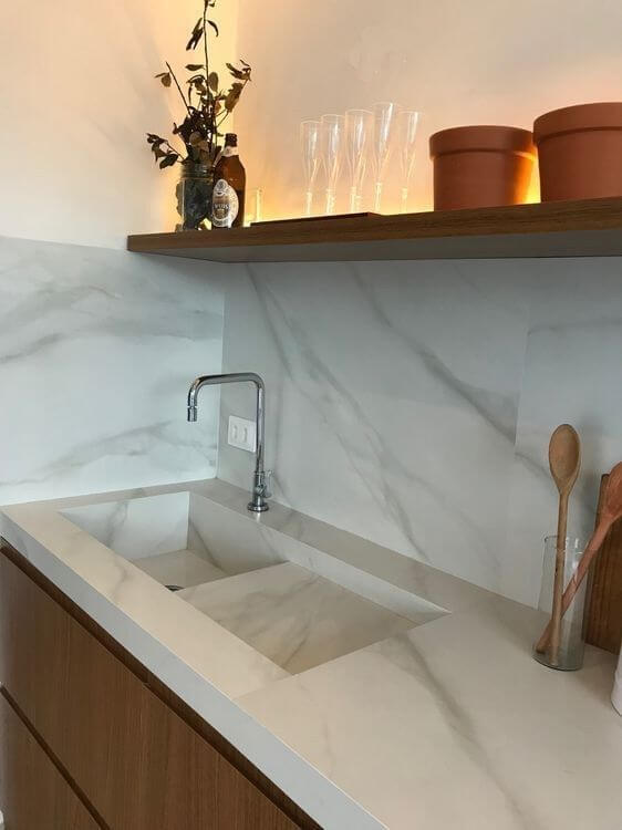 Pia de mármore na cozinha branca com prateleira de madeira