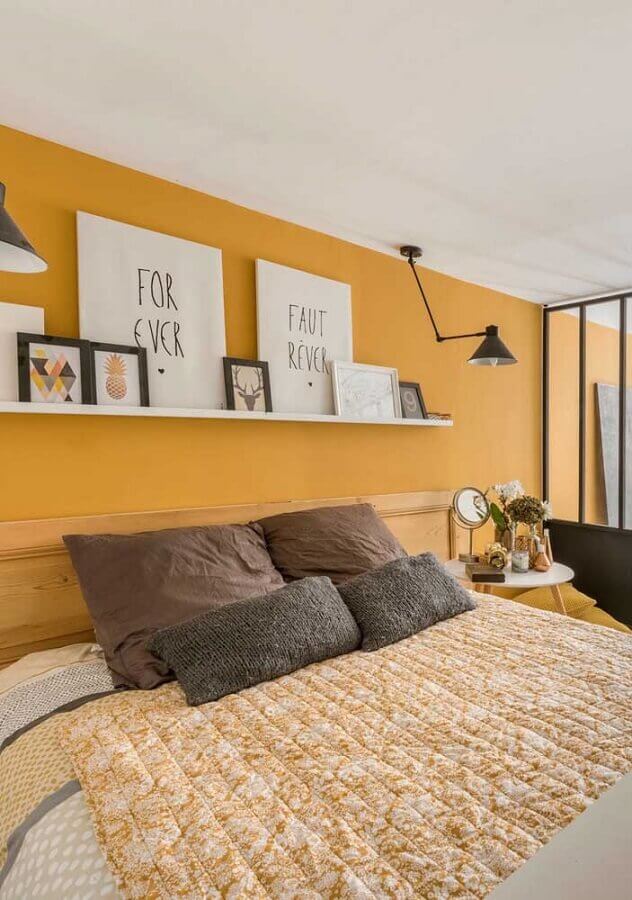 quarto amarelo decorado com cabeceira de madeira e prateleira para apoio de quadros Foto Pinterest