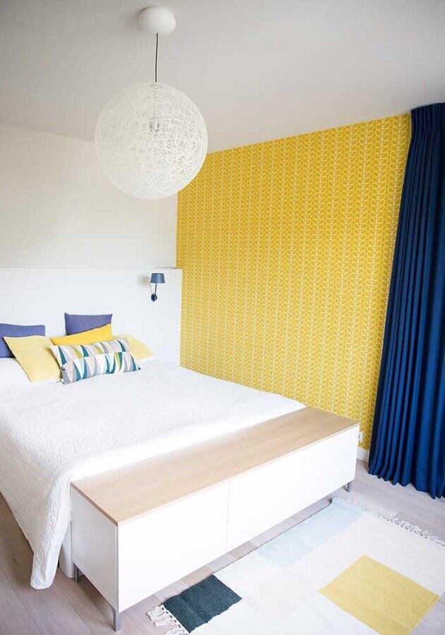 quarto amarelo e branco simples decorado com cortina azul e papel de parede Foto Assetproject