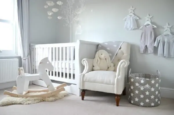 quarto de bebê cinza e branco com cabides suspensos 