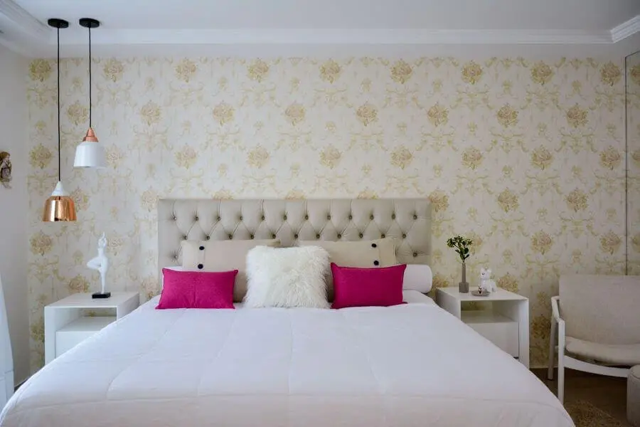 quarto de casal decorado com papel de parede floral e cabeceira capitonê