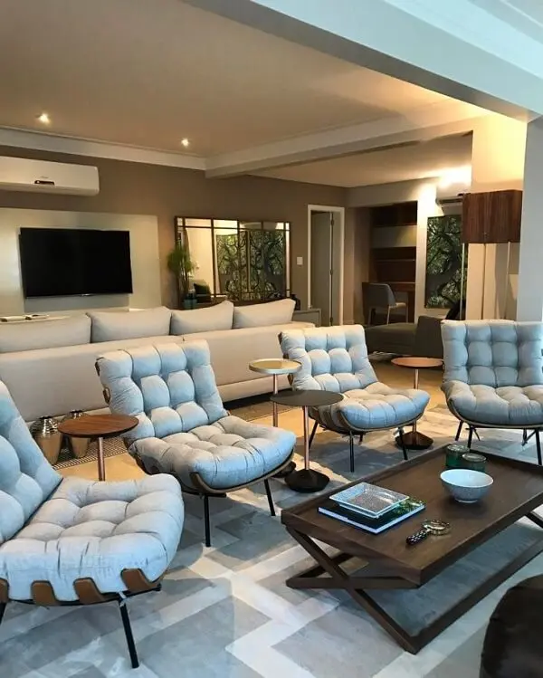 A poltrona costela forma uma linda divisória de ambientes, separando sala de estar e sala de tv