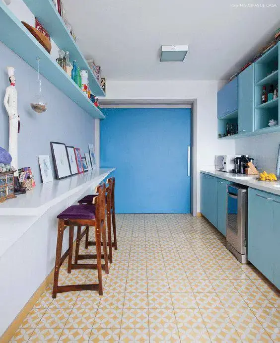 Armários azuis e pisos para cozinha em tons amarelos se harmonizam no projeto