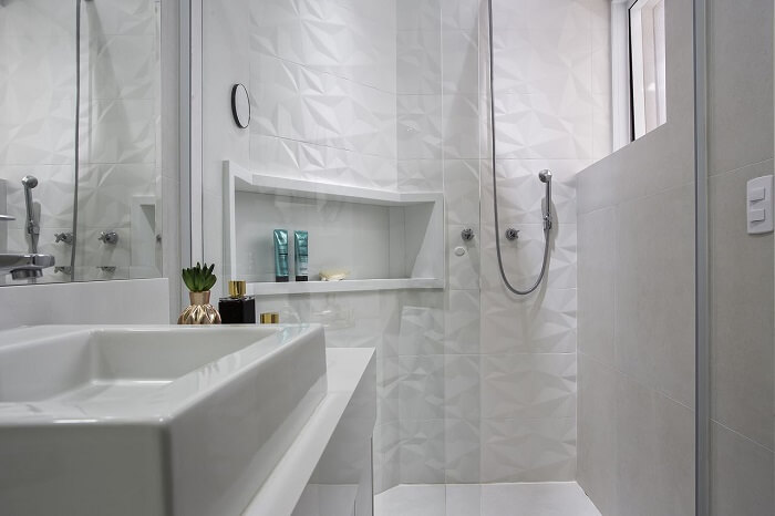 Box de vidro e parede com revestimento 3D decoram o banheiro. Fonte: MAV Arquitetura