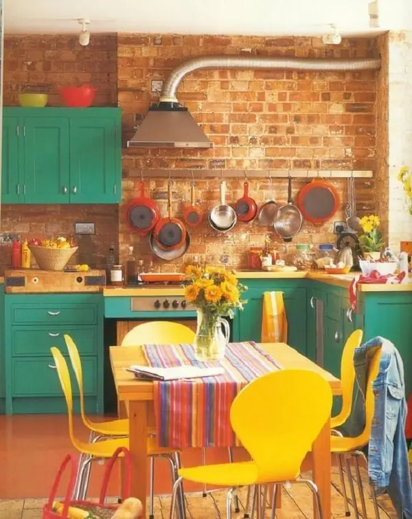 Parede de tijolinhos e cadeiras para cozinha coloridas trazem descontração para o espaço