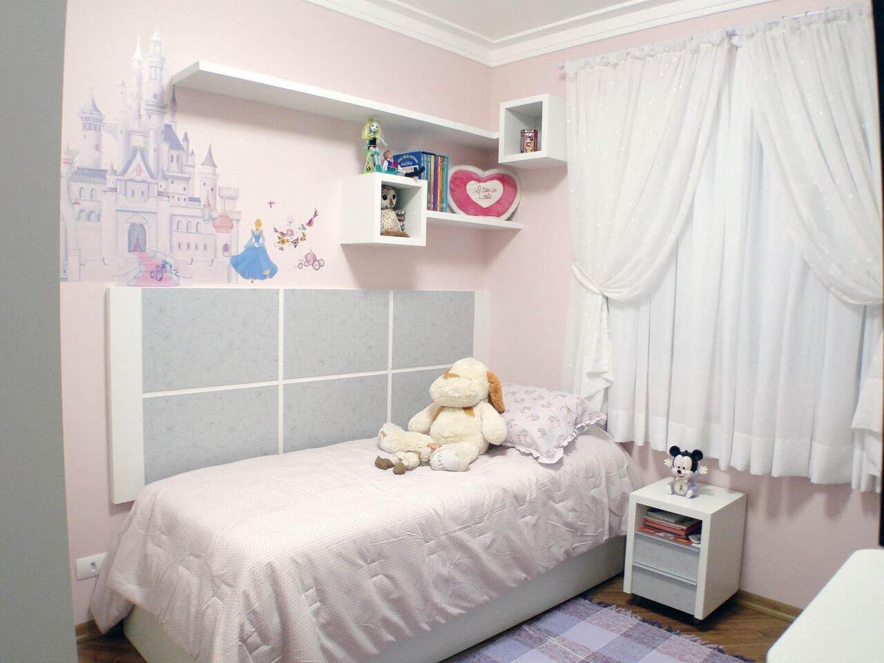 Quarto com cama infantil branca e parede com imagens das princesas