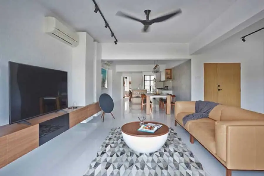 Sala de estar ampla decorada com sofá de couro e rack de madeira moderno