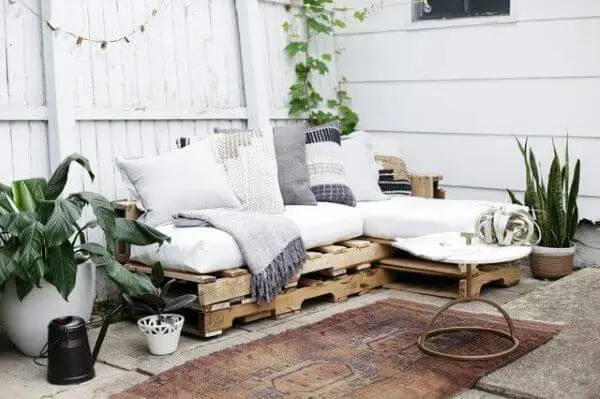 Sofá de palete com almofada e mantinha na varanda