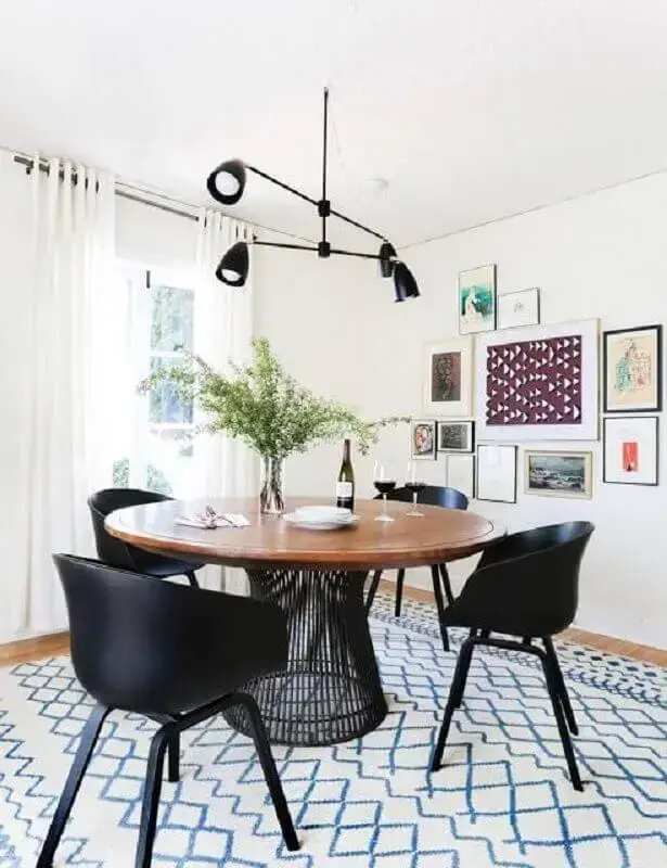cadeiras pretas para sala de jantar decorada com luminária moderna e mesa redonda Foto Archello