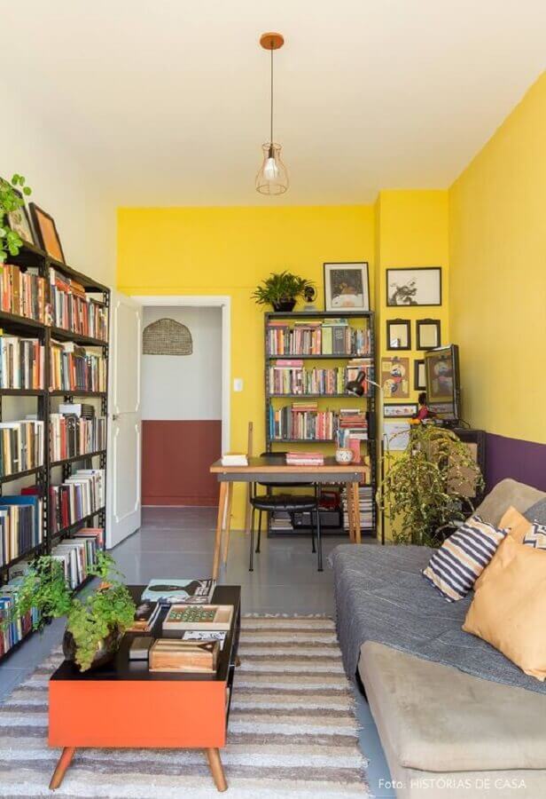 decoração de sala amarela com estante de livros e tapete listrado Foto Histórias de Casa