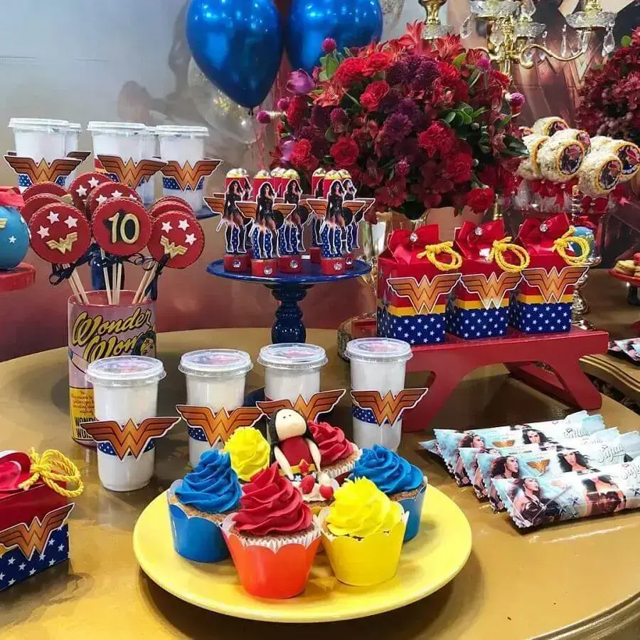 doces coloridos e arranjo de flores para decoração de festa mulher maravilha Foto Cajuartes Festas