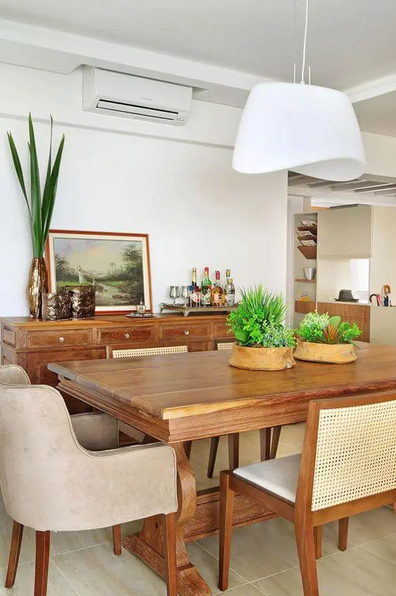 Mesa de jantar madeira rústica com lustre branco e plantas na decoração