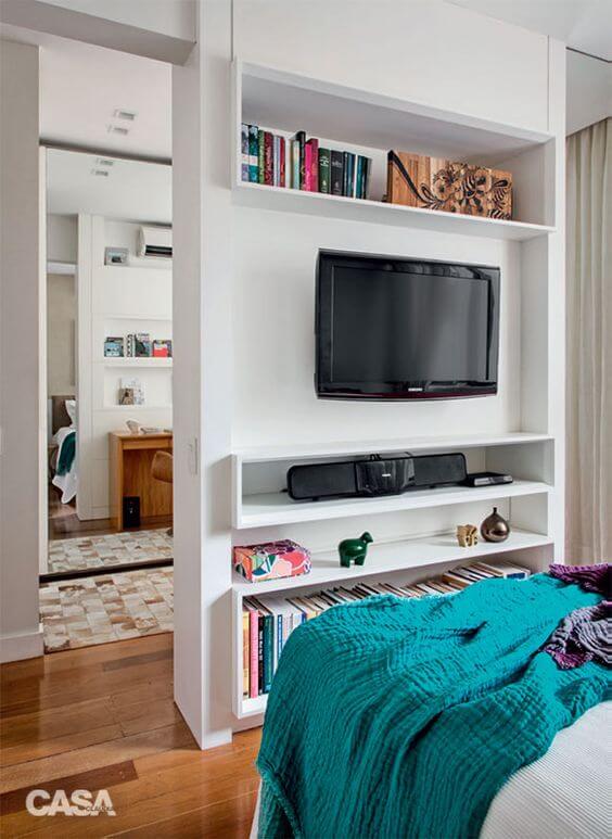 Use o painel para tv com prateleiras e nichos para organizar seu quarto 