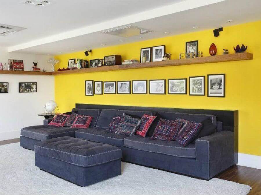 prateleira de madeira e sofá cinza para decoração de sala com parede amarela Foto Ricardo Lopes