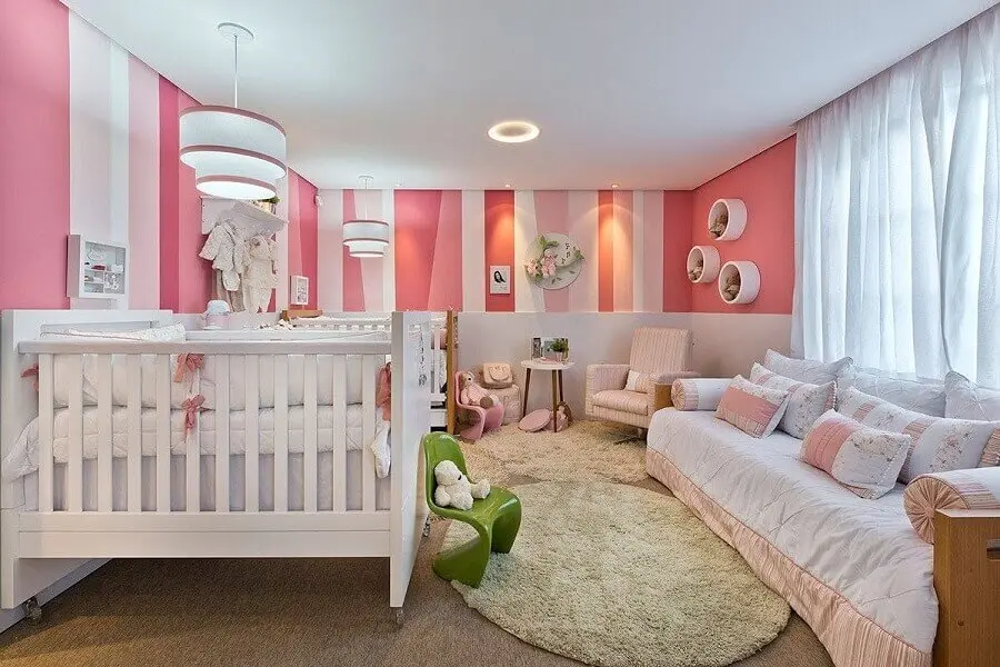 quarto de bebê rosa e branco decorado com papel de parede listrado e nichos redondos Foto Webcomunica