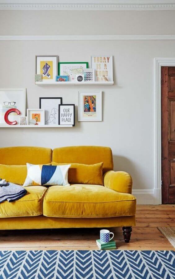 sofá para sala amarela decorada com prateleiras para quadros Foto Histórias de Casa