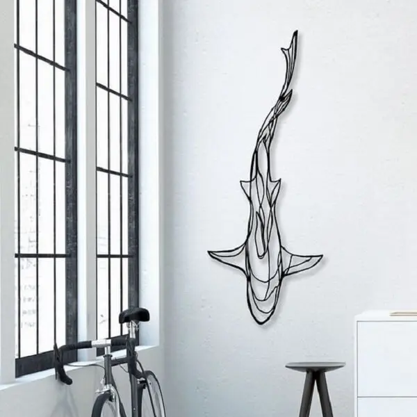 A escultura de ferro da parede forma a imagem de um tubarão