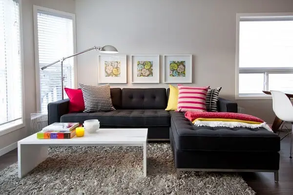 As almofadas coloridas se destacam sobre o sofá modular com chaise em tom preto
