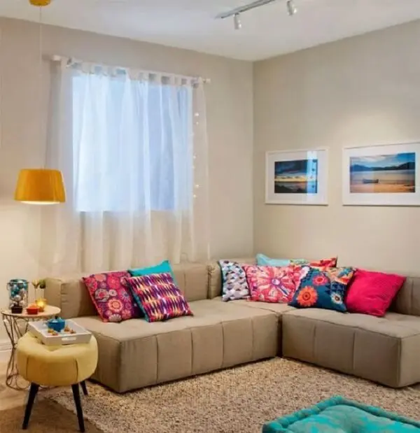As almofadas coloridas sobre o sofá modular trazem alegria para o espaço