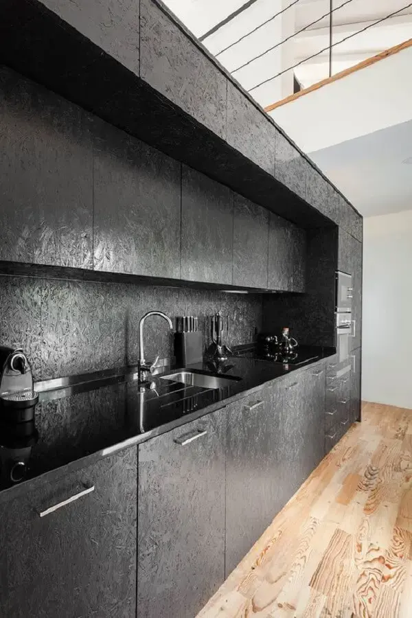 Móveis de cozinha em tom de preto e piso de madeira