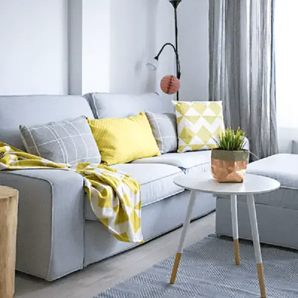 Sofá de cor neutra com almofadas e manta colorida reflete em um dos truques para melhorar a decoração da casa