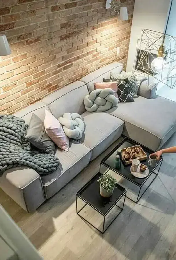 almofadas para sofá com chaise cinza em sala com parede de tijolo à vista Foto Futurist Architecture