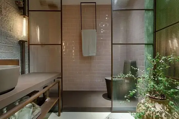 Banheiro sofisticado com divisória de vidro canelado