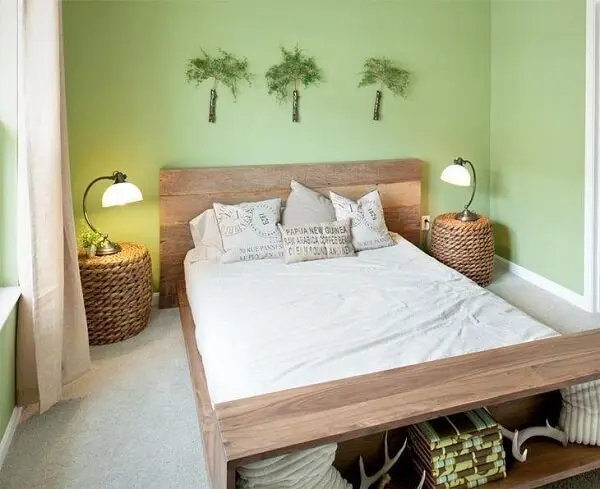 Criado mudo redondo posicionado ao lado da cama de casal é feito de cesto de vime
