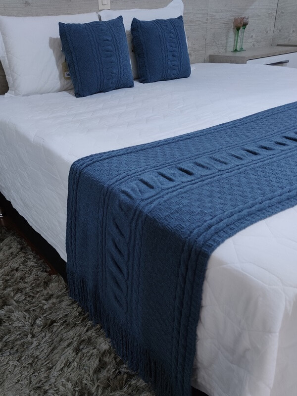 Peseira de cama azul marinho se destaca sobre o edredom branco. Fonte: Usufruto Home Decor