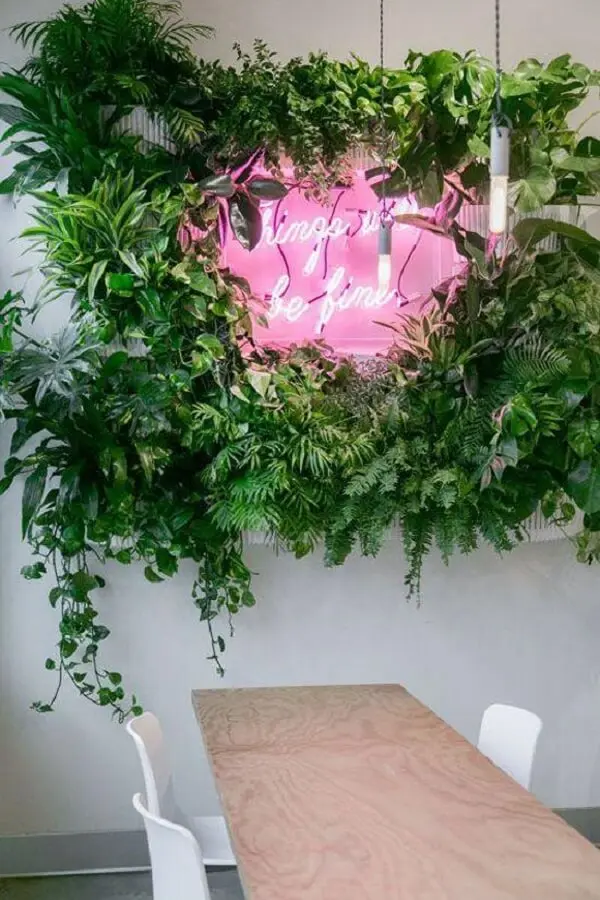 Sala de jantar com letreiro luminoso neon e jardim vertical artificial traz um toque tropical para a decoração