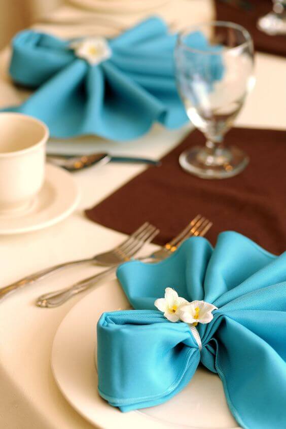 Como dobrar guardanapo de tecido azul com flores decorativas 