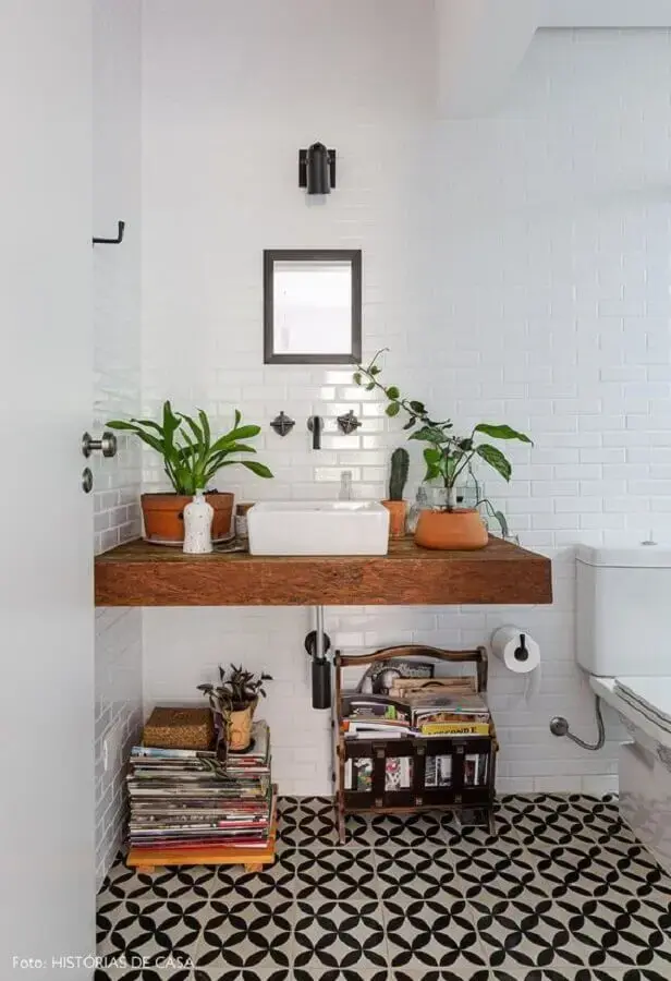 decoração com plantas no banheiro com bancada de madeira e piso preto e branco Foto Histórias de Casa