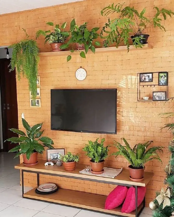 sala de estar decorada com prateleira suspensa para plantas e parede de tijolinho à vista Foto Pinterest