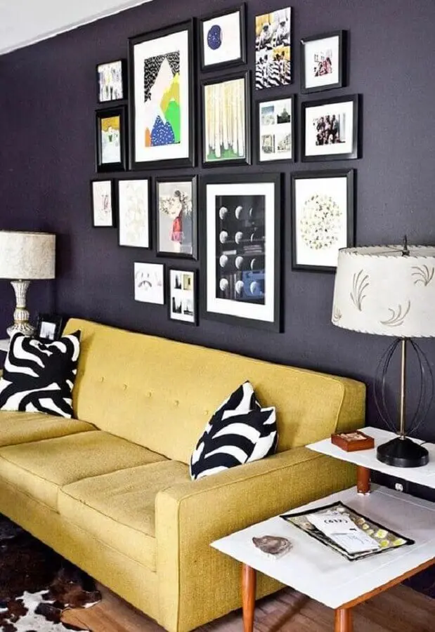 sala decorada com sofá amarelo e composição de quadros na parede preta Foto Simples Decoração
