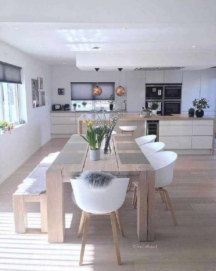 cozinha ampla com ilha decorada com cadeiras brancas e mesa com banco de madeira Foto Pinterest