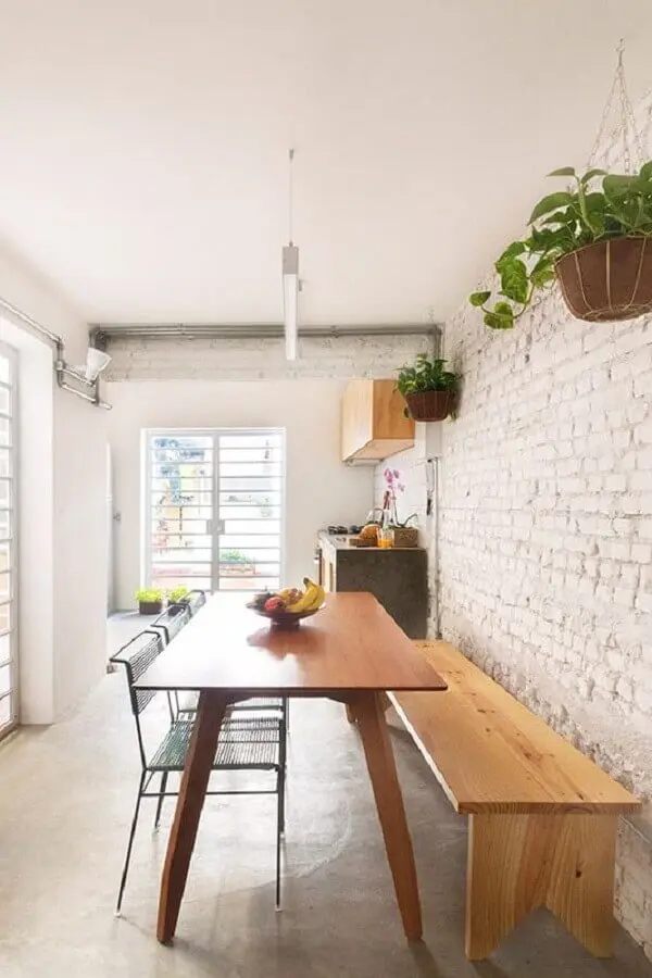 mesa com banco de madeira para sala de jantar com parede de tijolinho branca Foto INÁ Arquitetura