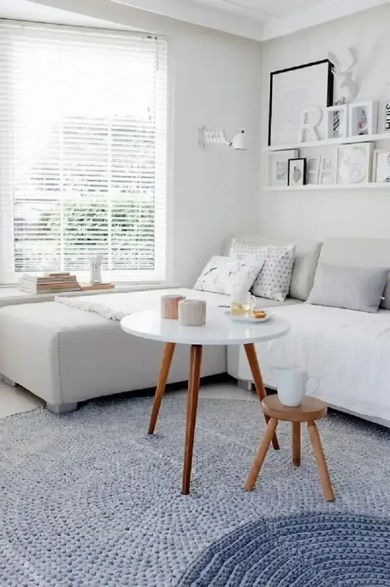 sala branca decorada com tapete de crochê cinza e mesa de centro redonda para sala Foto Archzine
