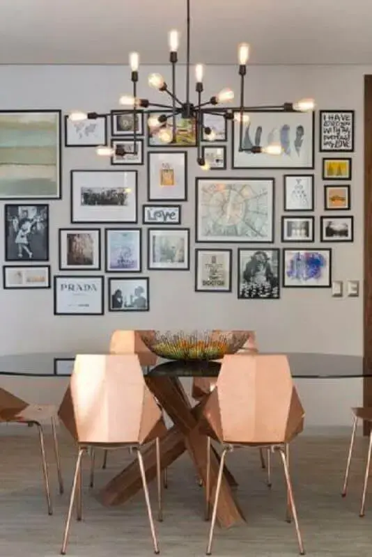 sala de jantar moderna decorada com vários quadros e lustre para mesa de jantar com cadeiras rose gold Foto Conexão Décor
