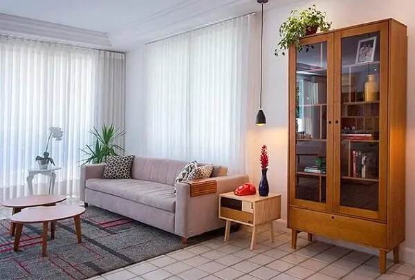 A cristaleira de madeira maciça complementa a decoração da sala de estar