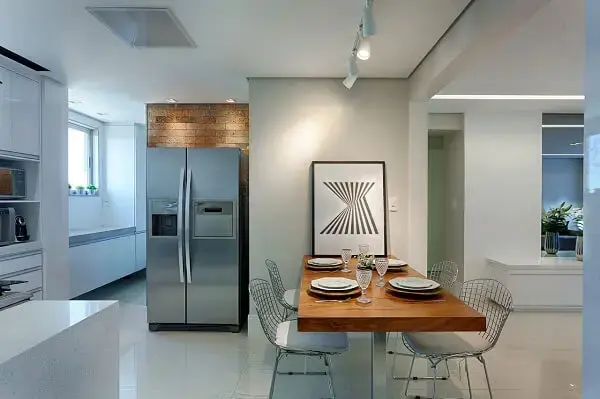 A iluminação em trilho branca destaca a presença do quadro de decoração para cozinha