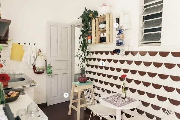 A mesa pequena para cozinha com estrutura branca fica discreta diante do papel de parede do cômodo