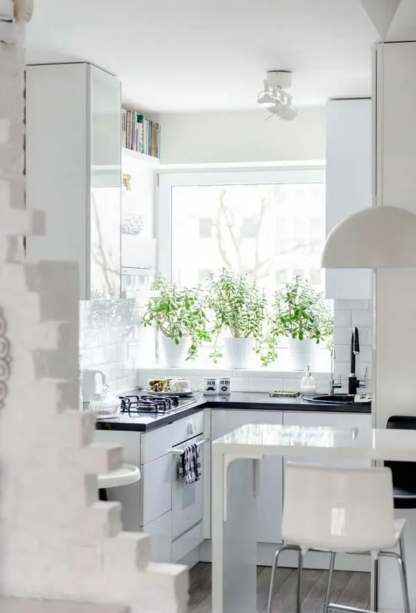 A mesa pequena para cozinha em tom branco se conecta com o restante da decoração