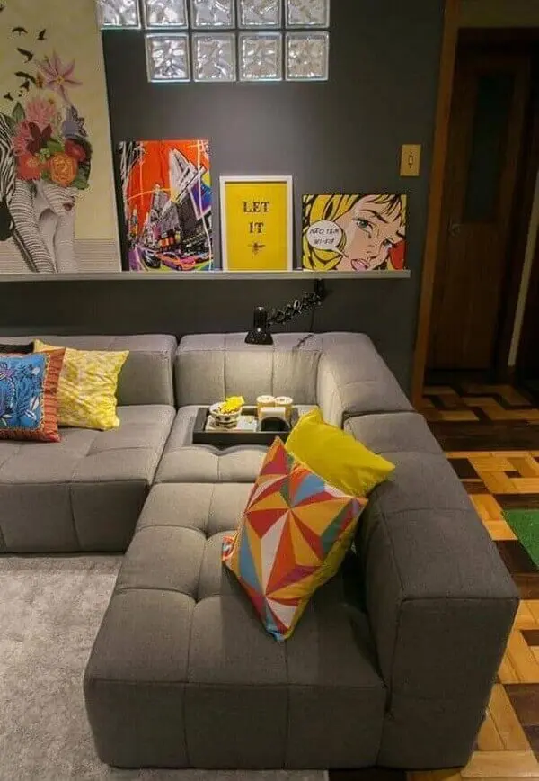 As almofadas coloridas se destacam sobre o sofá de canto cinza
