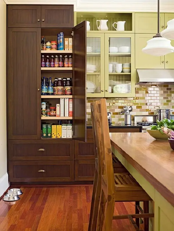 O armário para despensa de cozinha feito em madeira escura se destaca na decoração do ambiente
