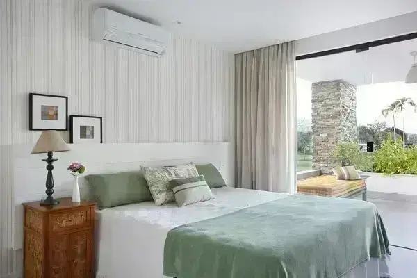 O papel de parede com listras verdes traz um toque suave na decoração do quarto
