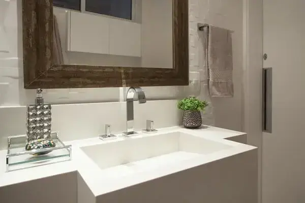 O revestimento 3D para banheiro branco destaca a presença do espelho com moldura de madeira