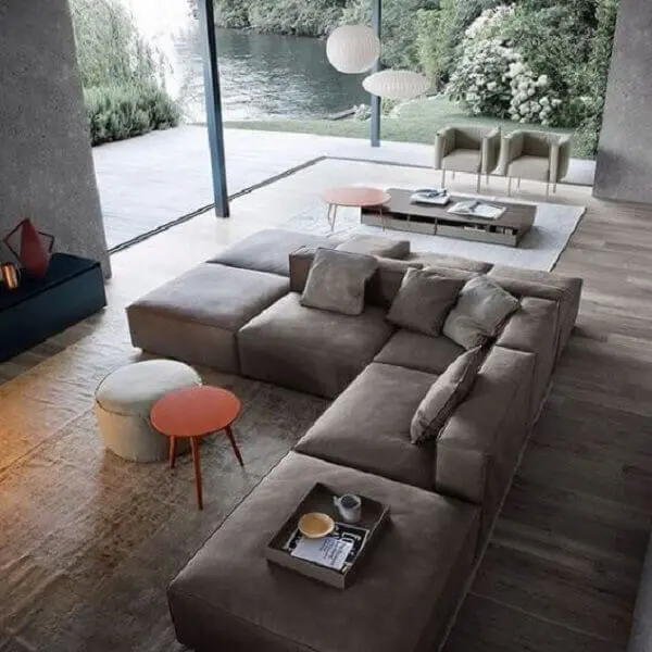O sofá de canto cinza separar os ambientes integrados e acomoda várias pessoas