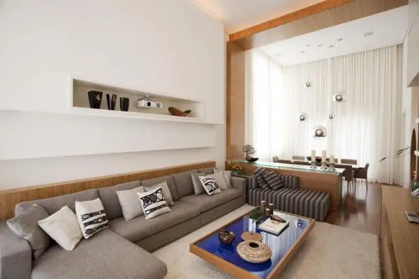 Para uma decoração clean combine o sofá de canto cinza claro com parede branco